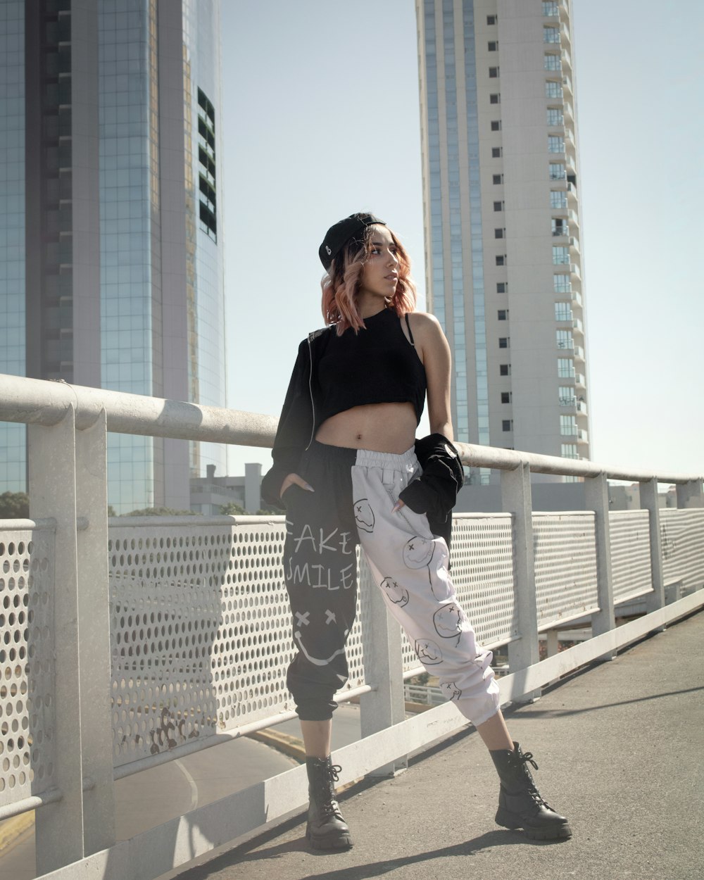 a woman standing on a bridge in front of tall buildings