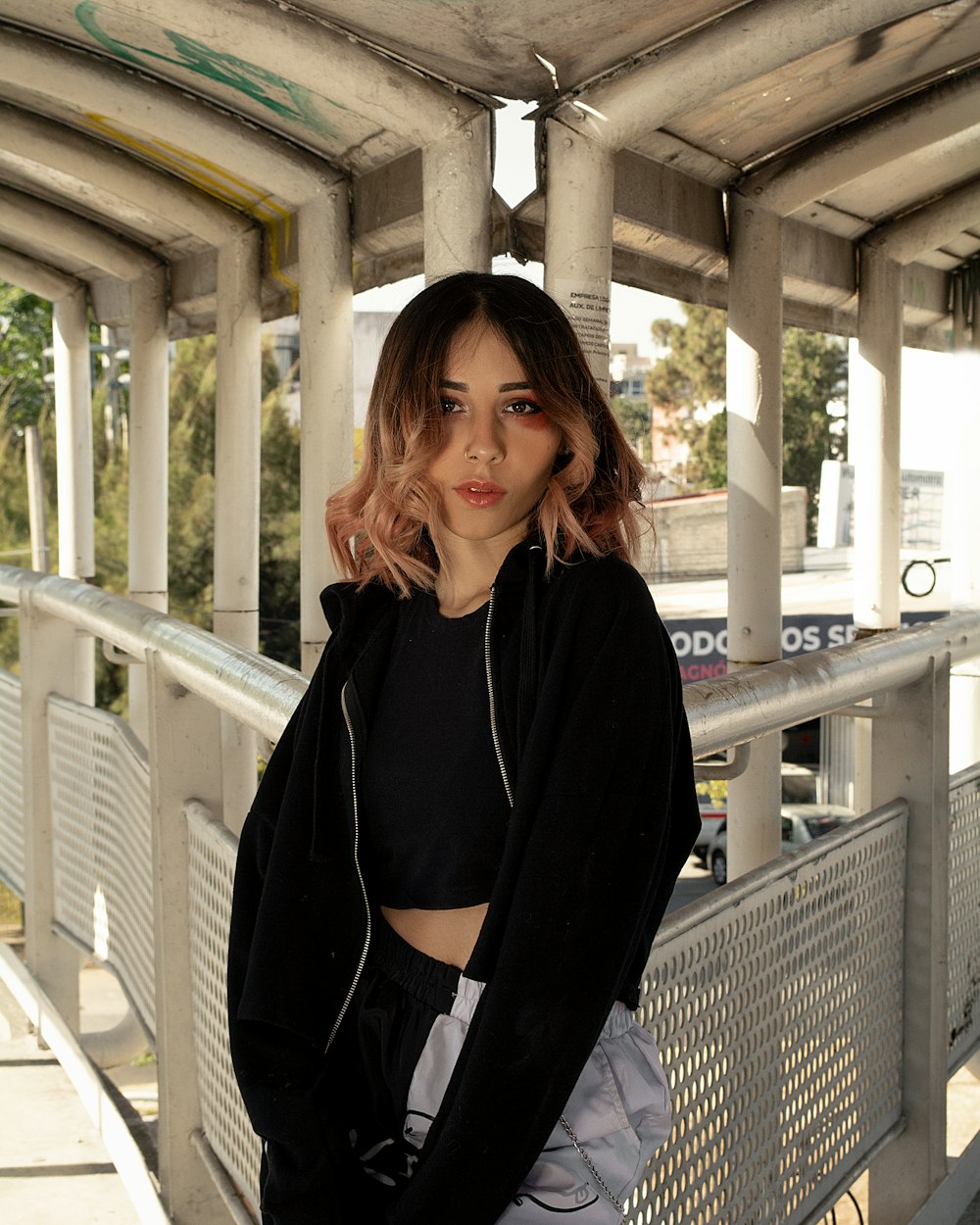 a woman standing on a bridge with her hands in her pockets