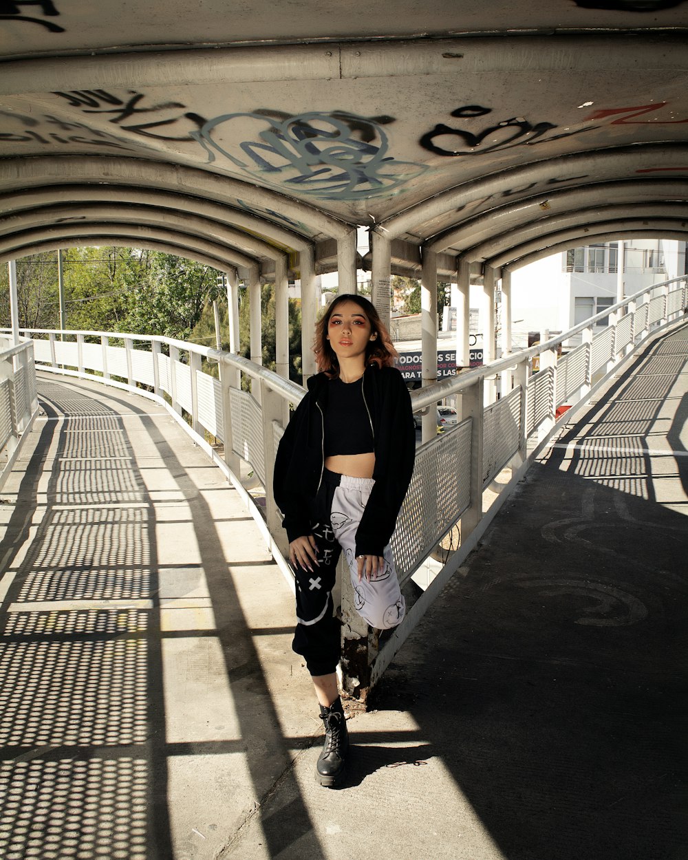 a woman standing on a bridge with a skateboard