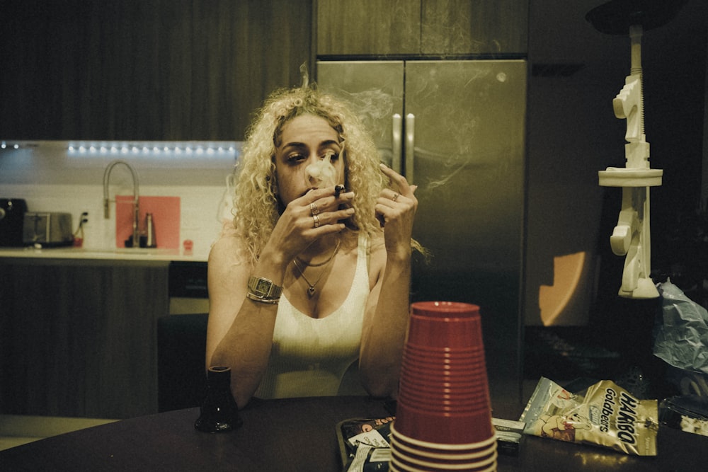 a woman sitting at a table smoking a cigarette