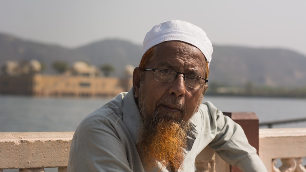 a man with a beard and glasses sitting on a bench