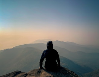 a person sitting on top of a mountain overlooking a valley
