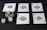 Five playing cards, all aces of spades, are arranged on a dark surface. Beside the cards, there is a stack of poker chips with two dice on top. Three additional dice are placed nearby, with both the poker chips and dice featuring a combination of red, blue, and white colors.