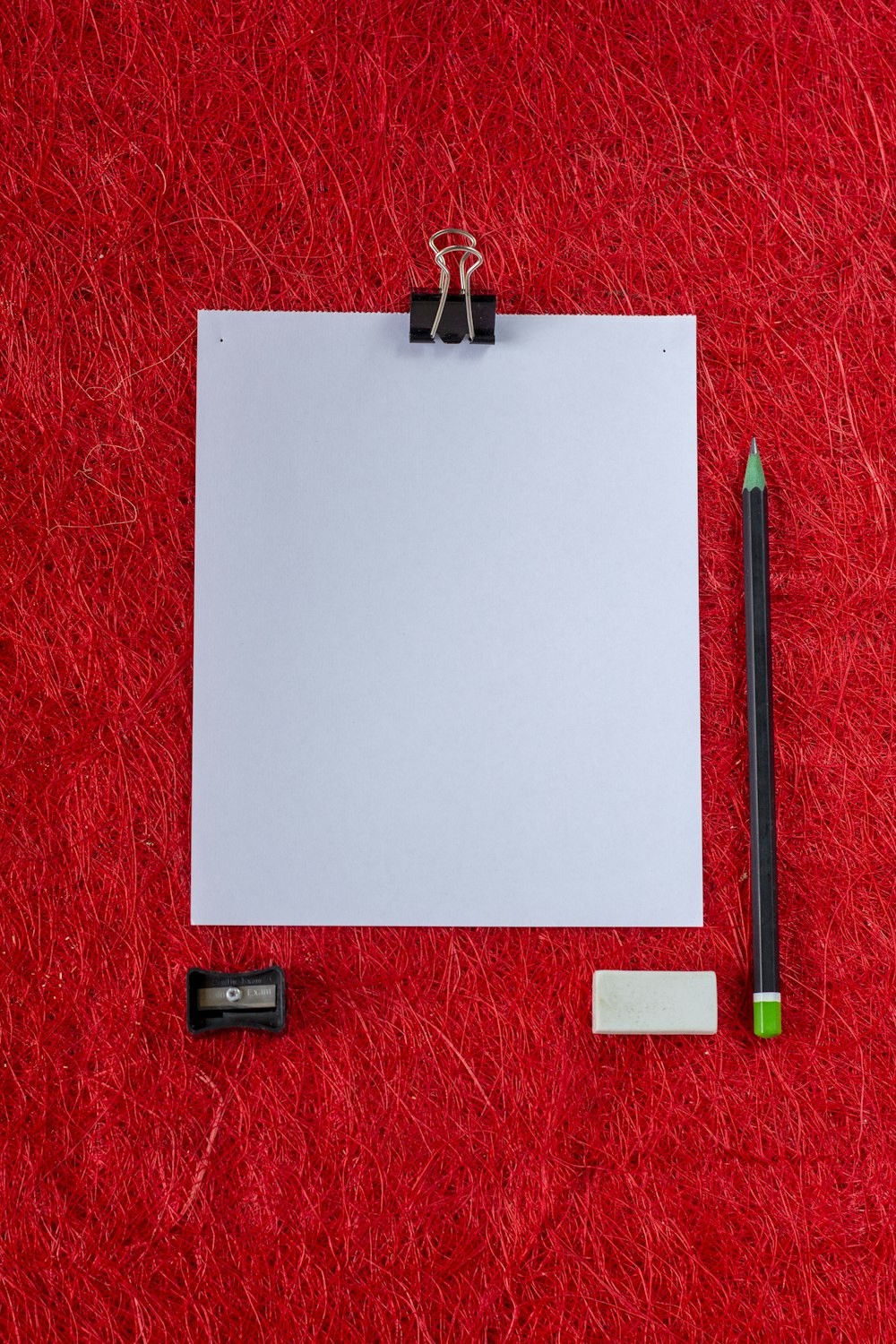 a piece of paper, pencil and eraser on a red carpet