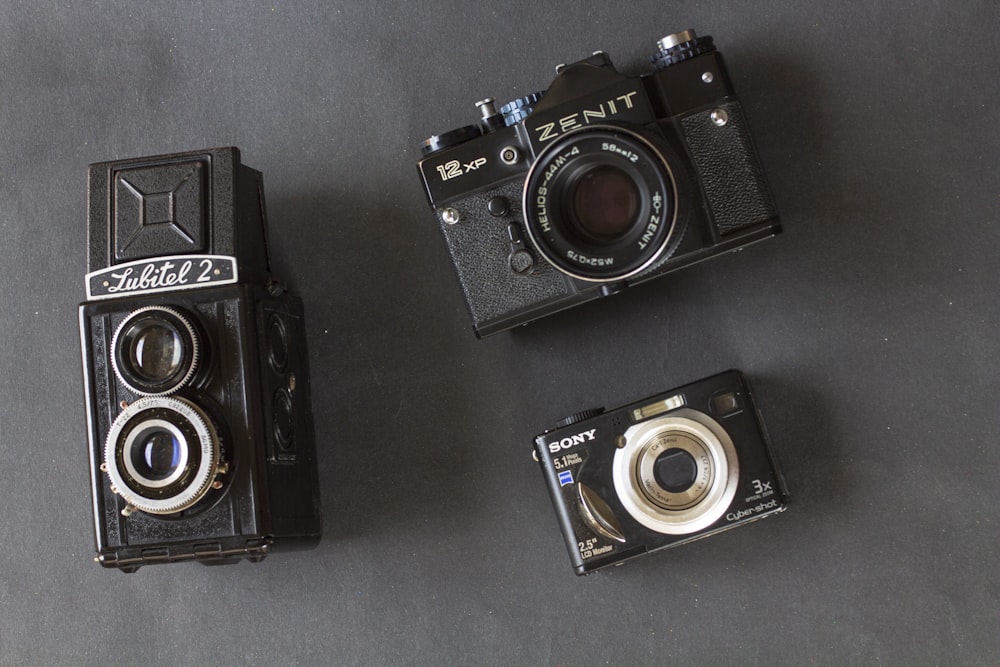 three old cameras sitting next to each other on a table