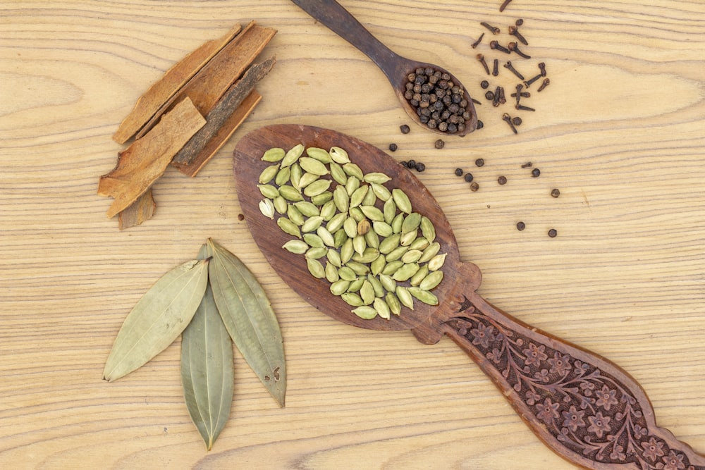 a wooden spoon filled with seeds on top of a wooden table