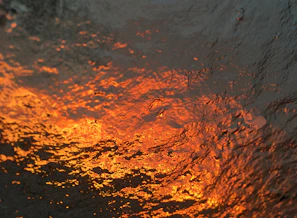 Close-up of flux granules with a steel gray and molten orange color palette highlighting texture