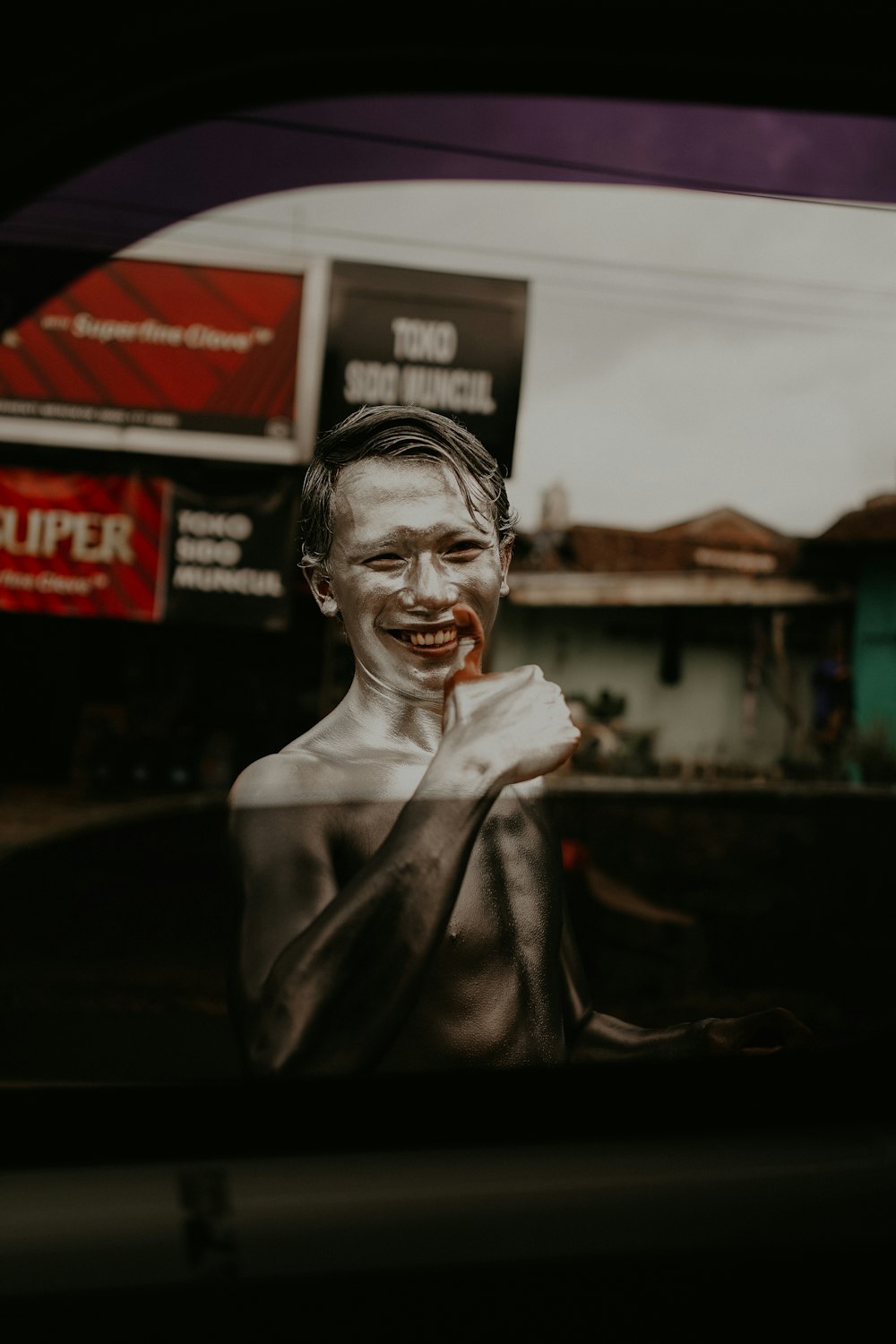 a man with a bloody face is seen through a car window