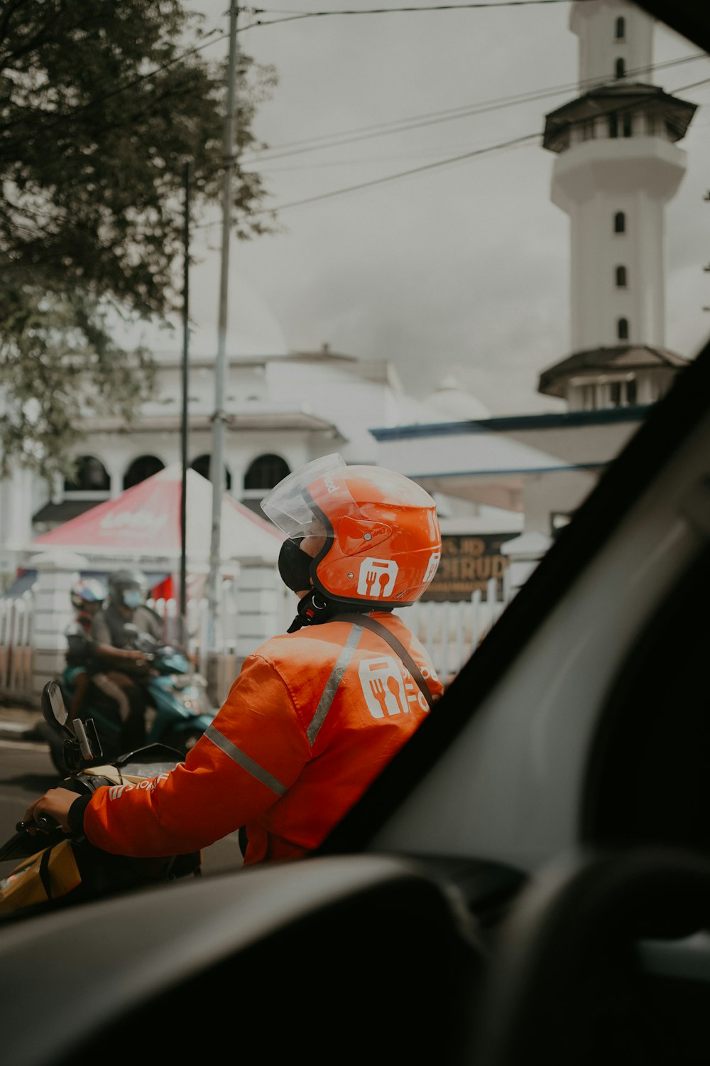 a man in an orange safety jacket riding a motorcycle