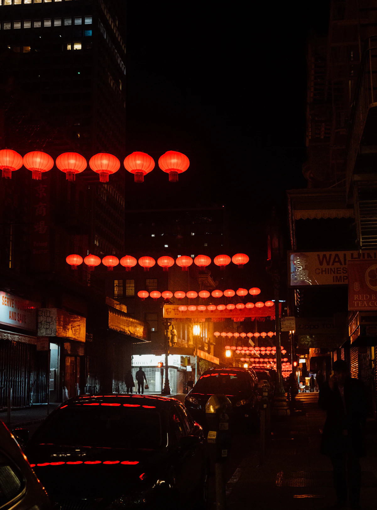 Red lanterns glowing above a Chinatown street at night