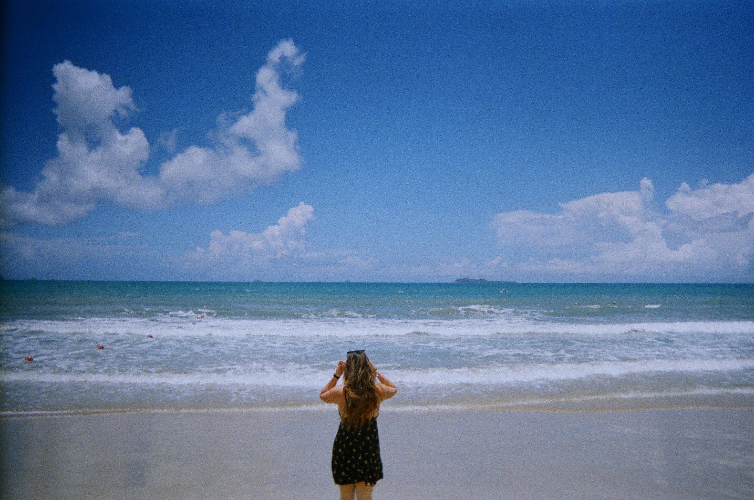a woman standing on top of a beach next to the ocean