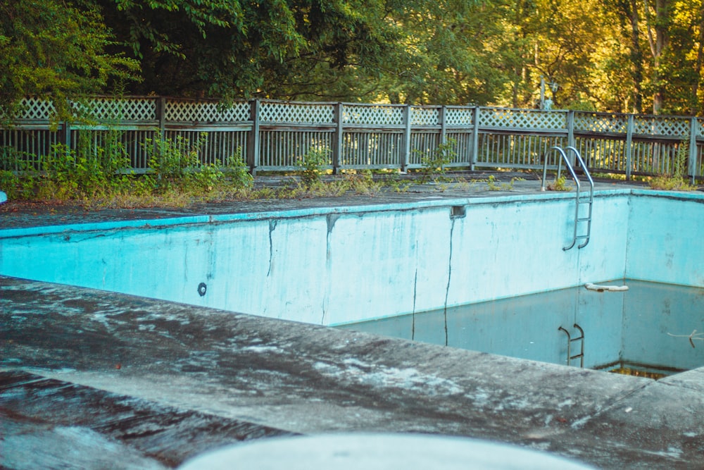 an empty swimming pool surrounded by a wooden fence