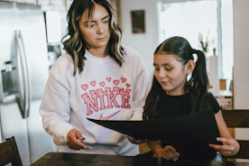 a woman standing next to a little girl in a kitchen