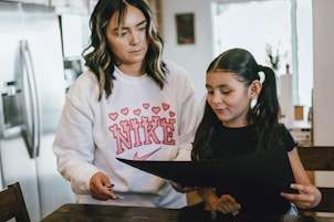 a woman standing next to a little girl in a kitchen