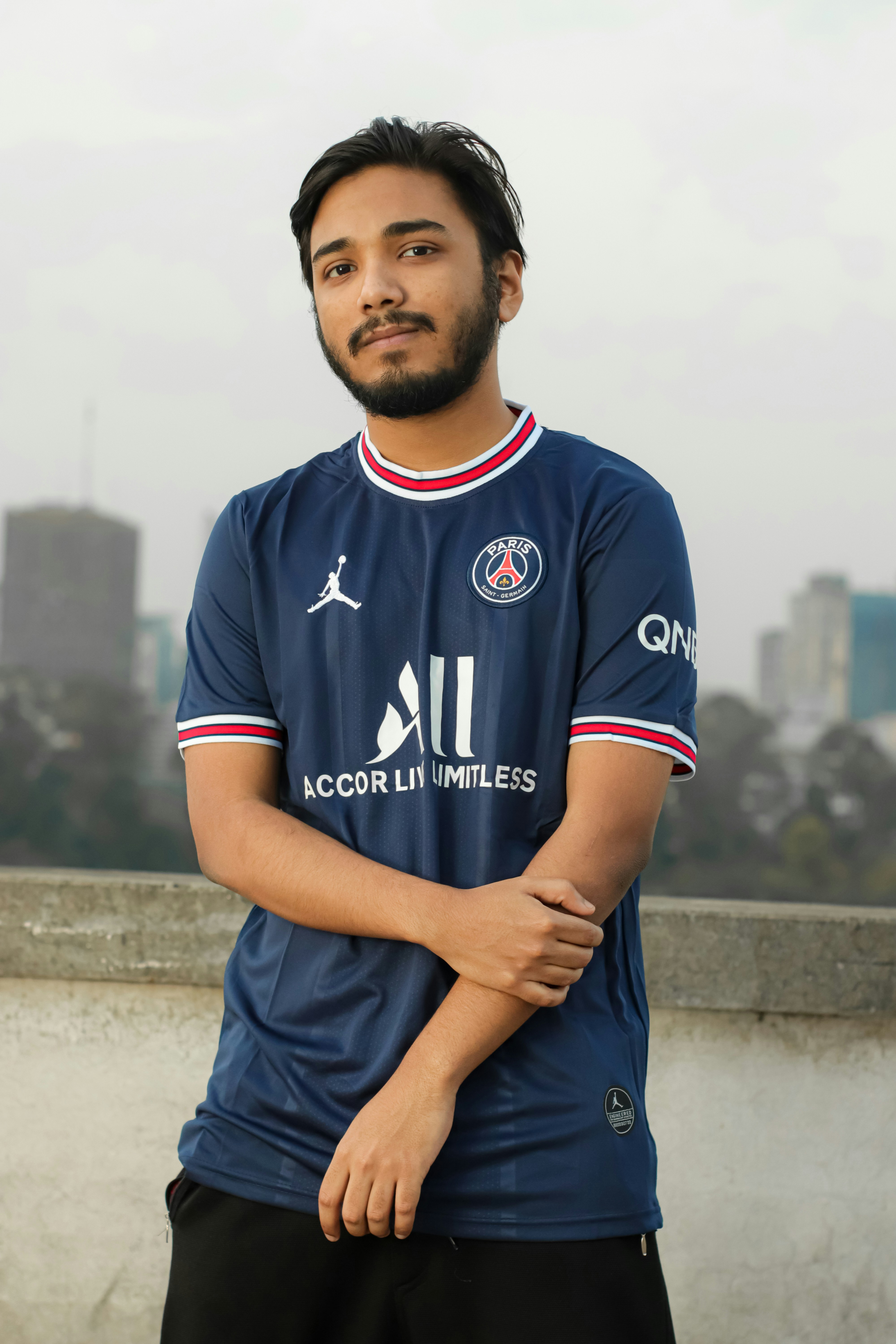 a man standing with his arms crossed in front of a city skyline