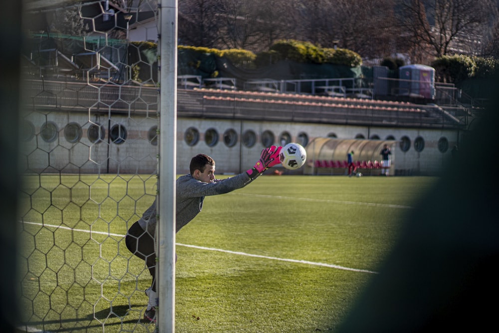 a soccer goalie catches the ball during a game