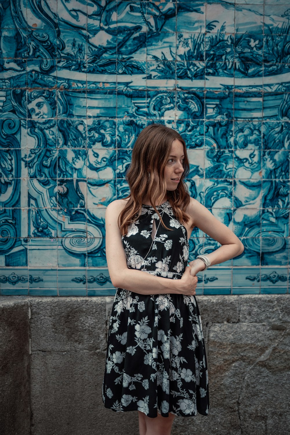 a woman standing in front of a blue tile wall