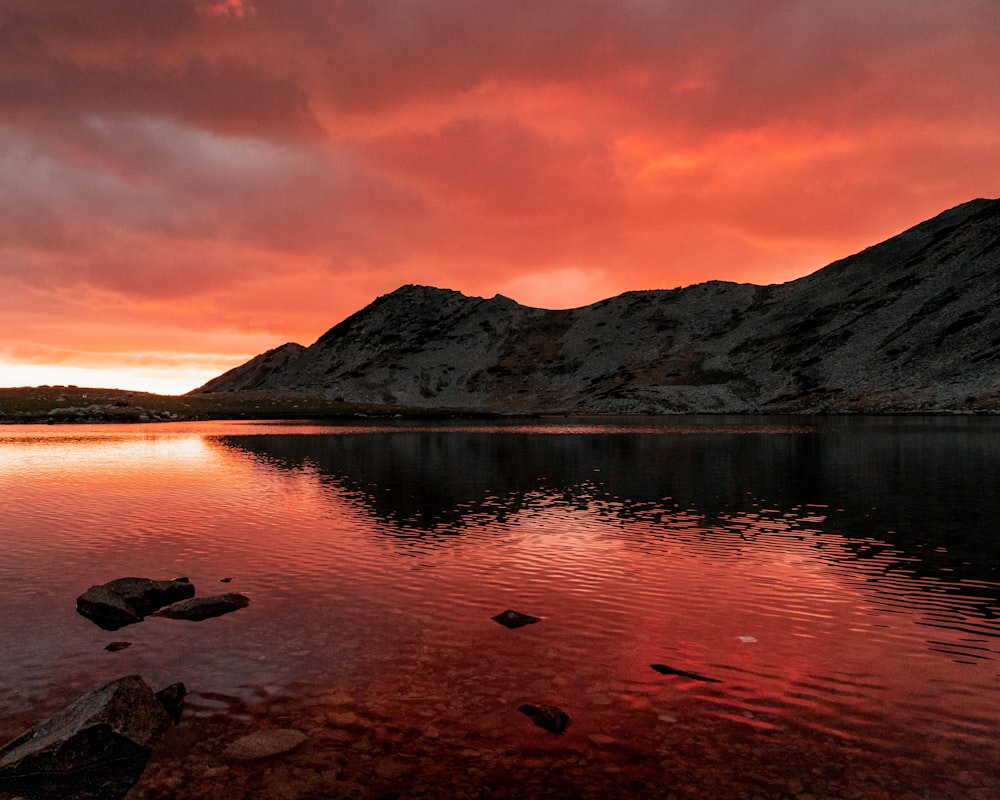 a lake with rocks in the water and a mountain in the background