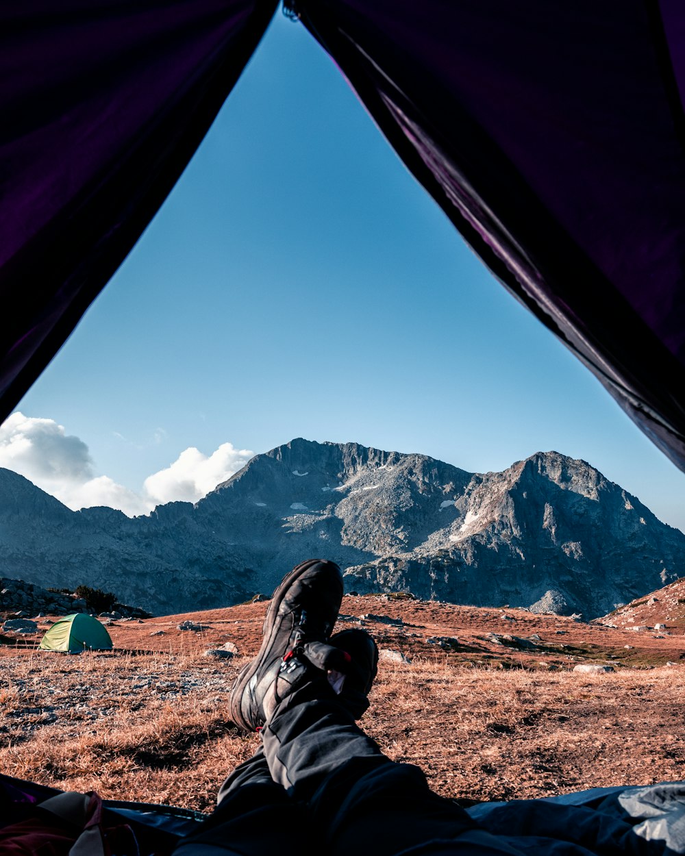 a person laying in a tent with mountains in the background