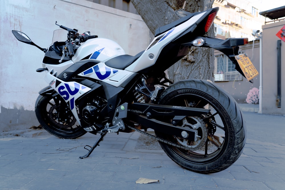 a white and blue motorcycle parked next to a tree