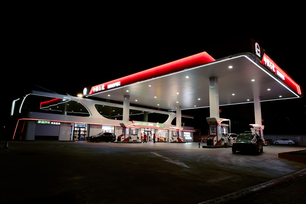 a gas station lit up at night with cars parked