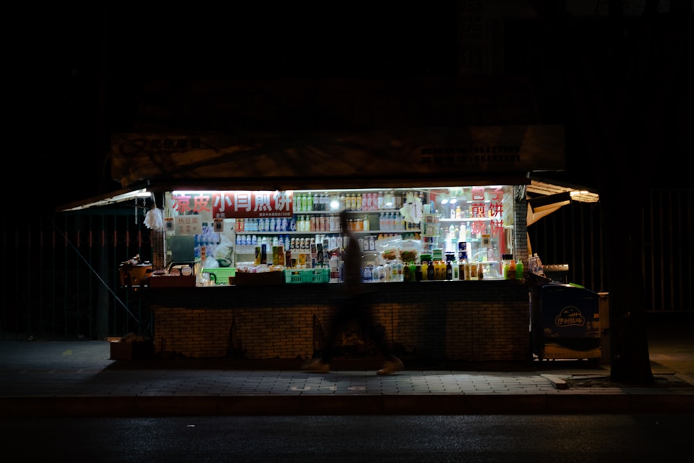 Un uomo che cammina davanti a uno stand di cibo di notte