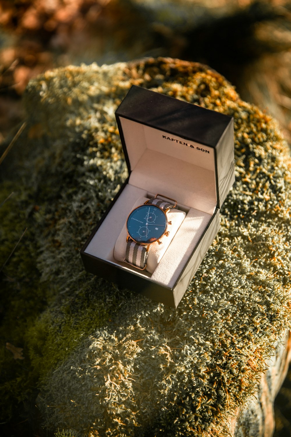 Un reloj sentado en una caja sobre una roca