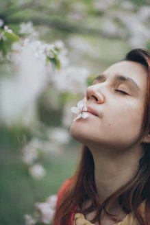 a woman with her eyes closed and a flower in her mouth
