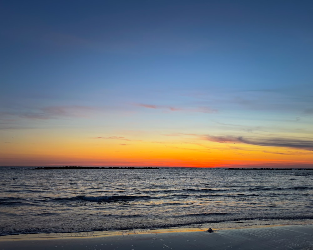 the sun is setting over the water at the beach