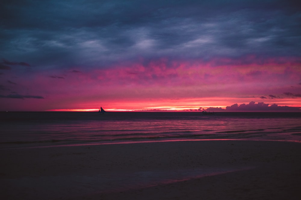 the sun is setting over the ocean on a cloudy day