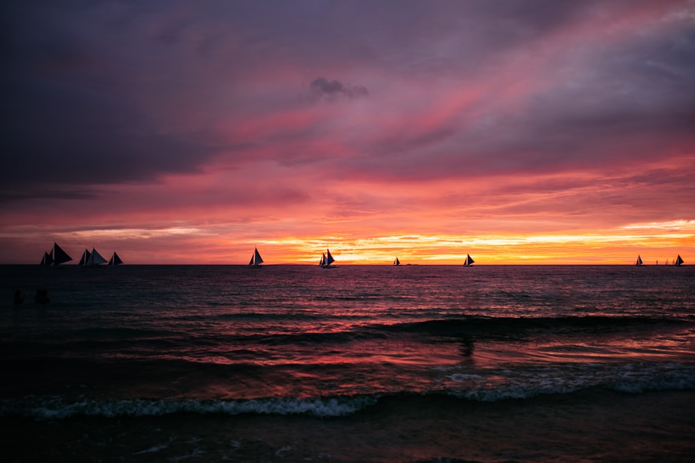 a sunset with sailboats in the distance