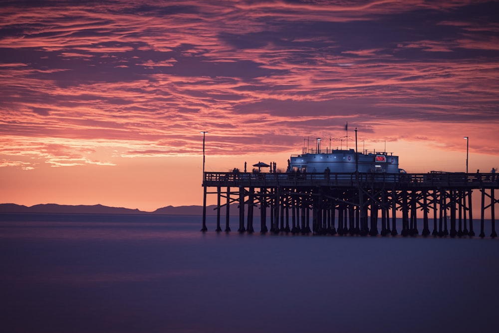 a pier with a building on top of it at sunset