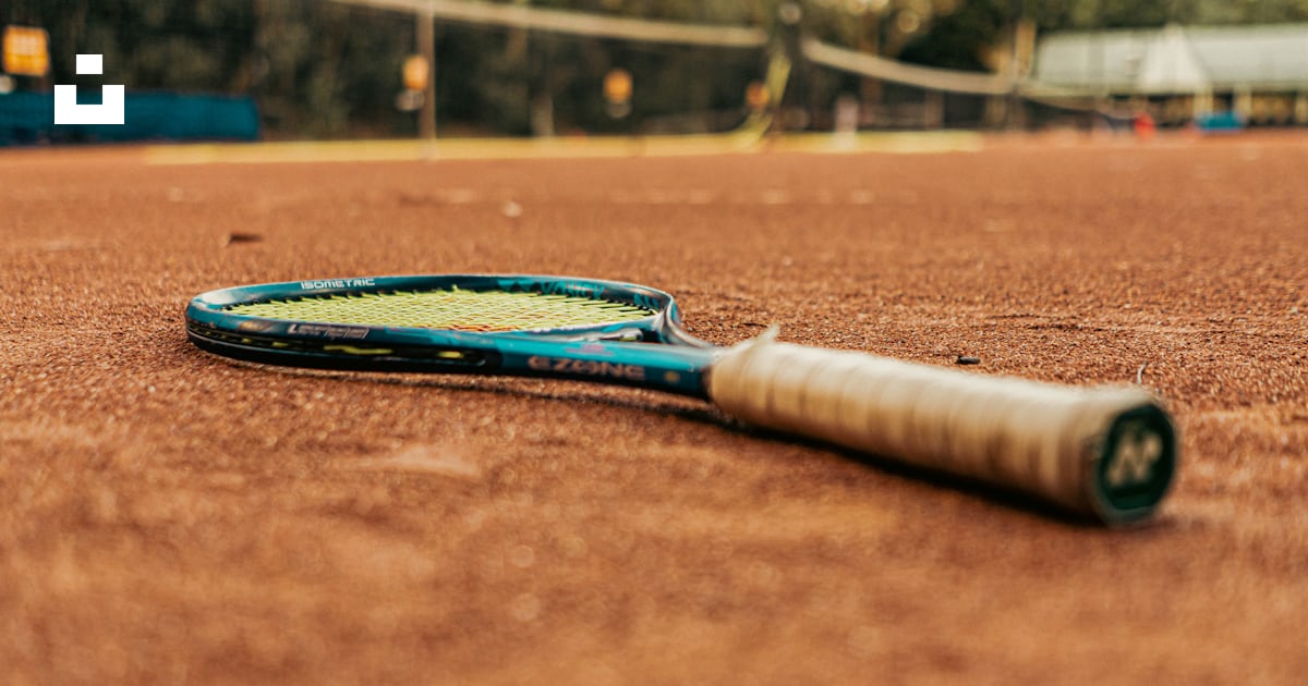 A tennis racket laying on a tennis court photo – Free Racket Image on ...