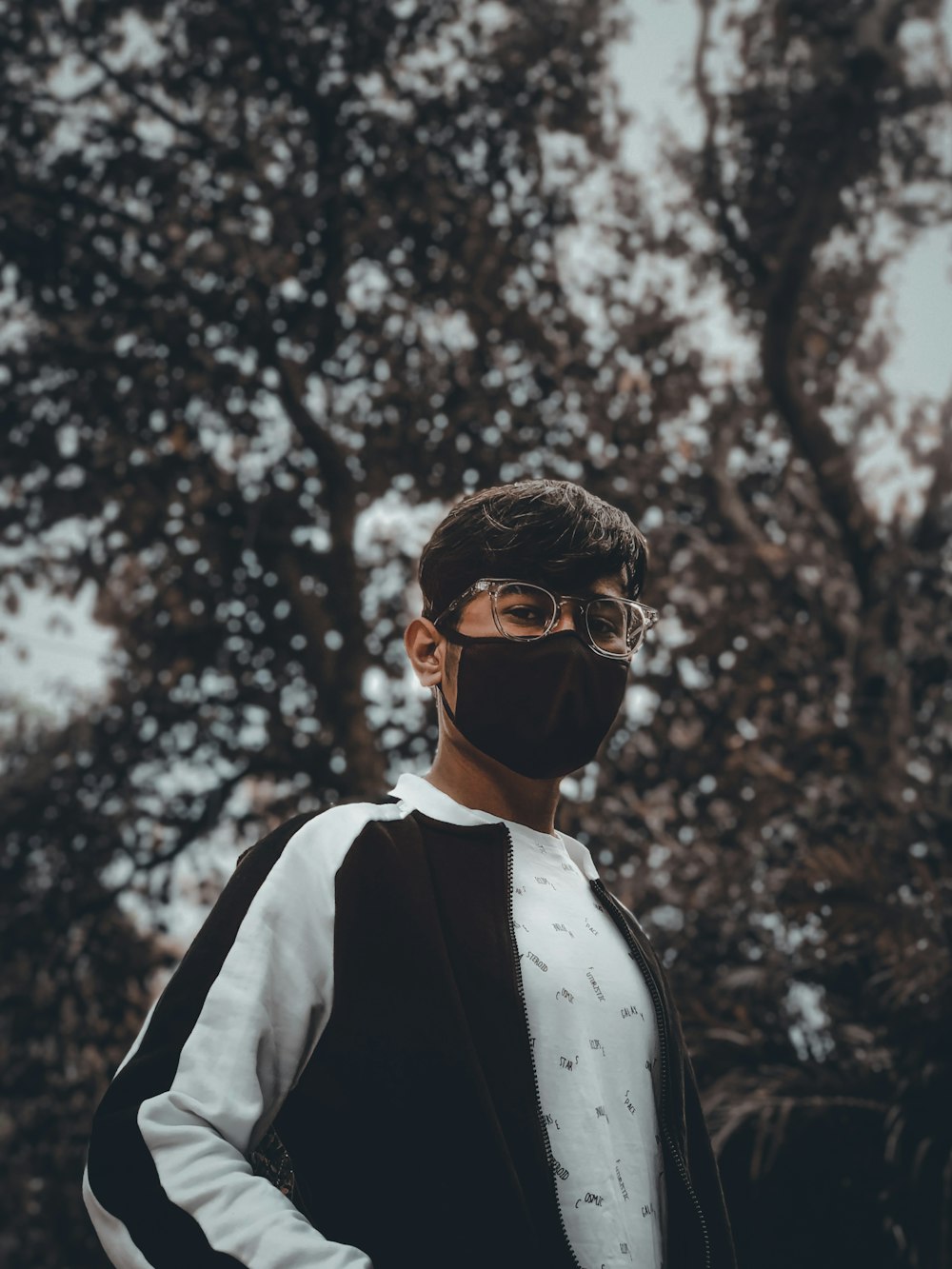 a man wearing a face mask standing in front of trees