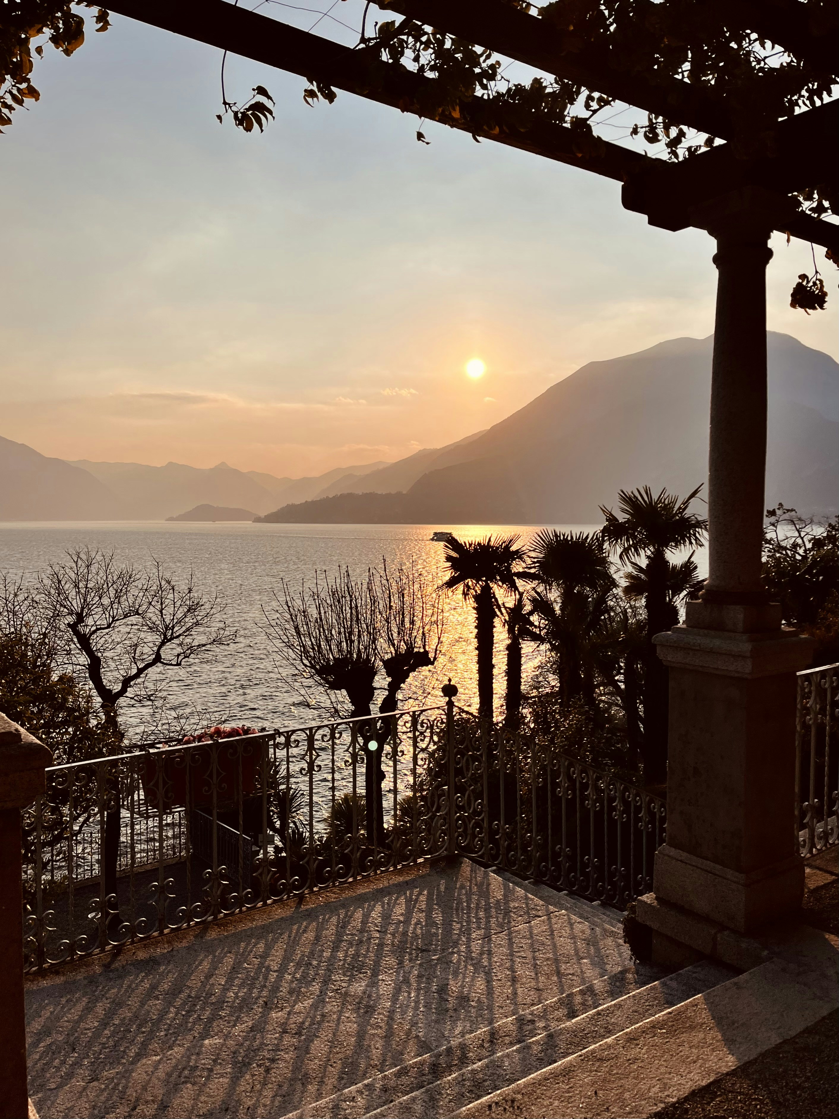 the sun is setting over the water and mountains