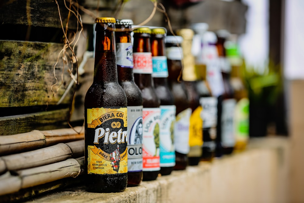 a row of beer bottles sitting on top of a wooden shelf