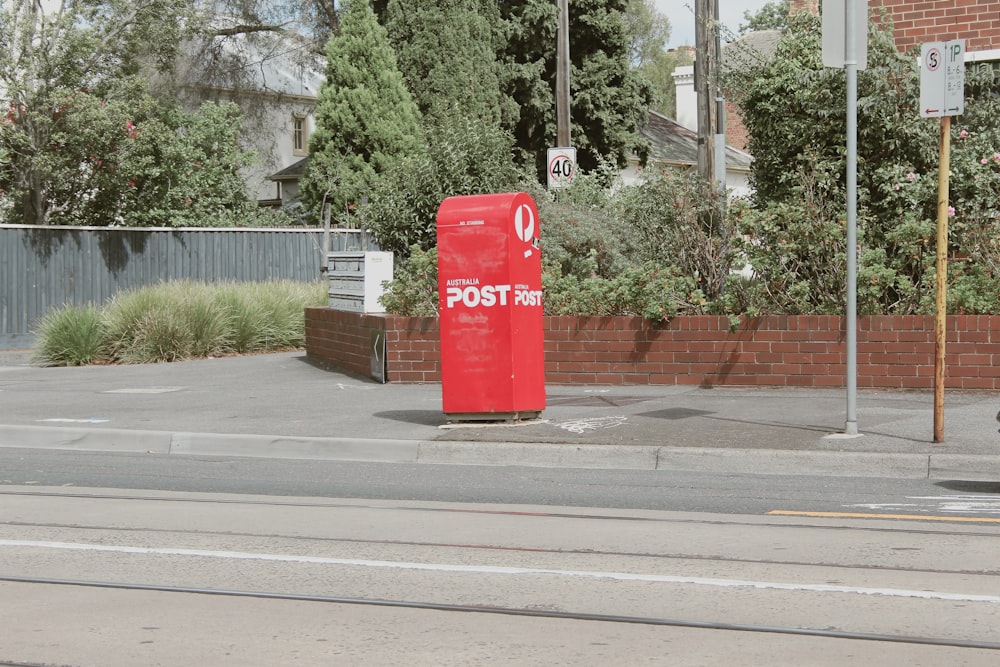 a red post box sitting on the side of a road