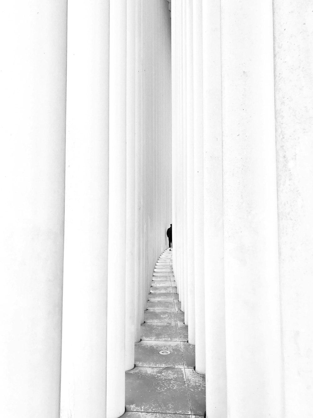 a person standing between two rows of white pillars