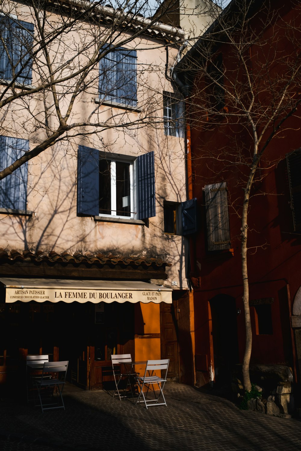 a building with blue shutters and a tree in front of it