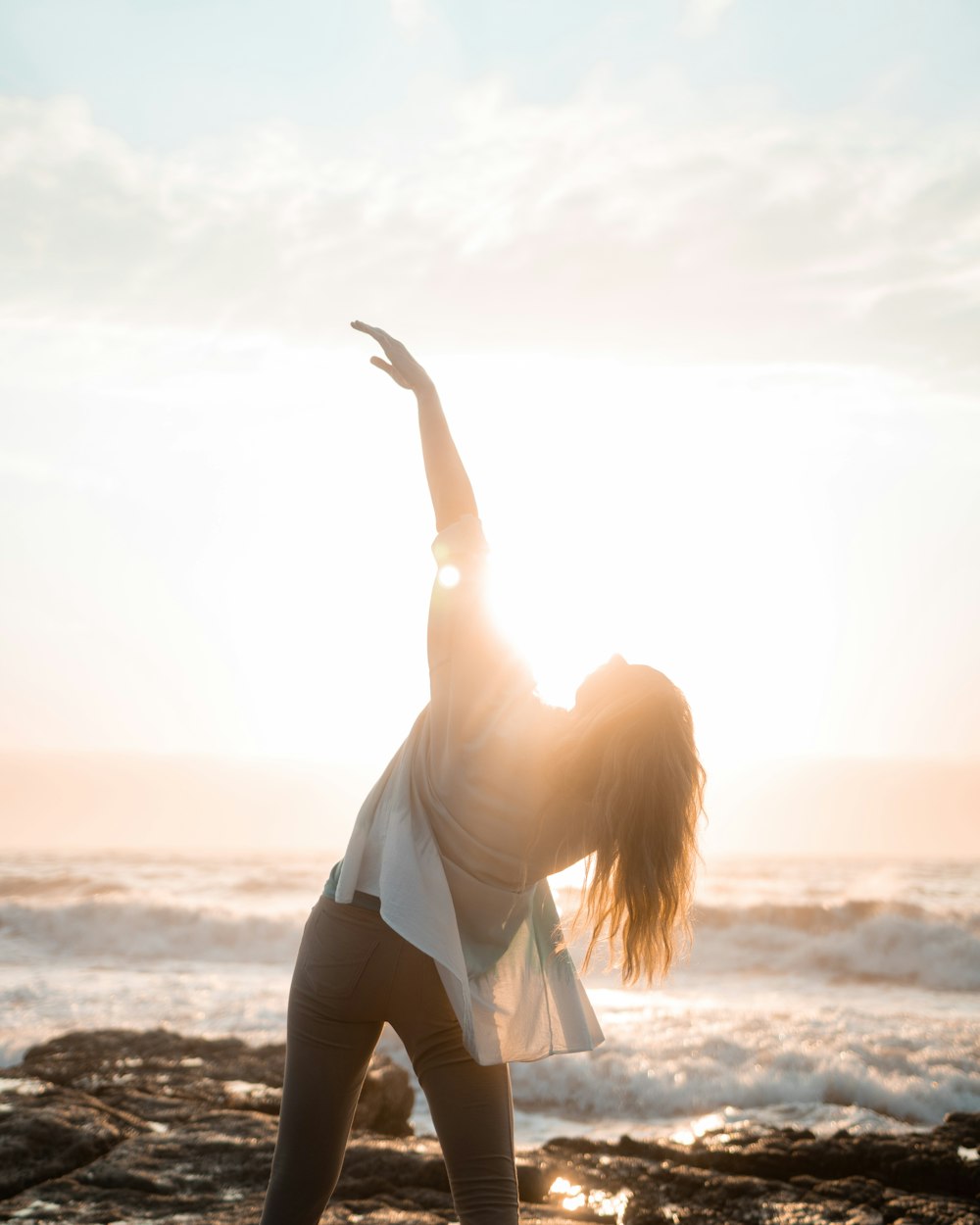 a woman doing yoga on the beach at sunset