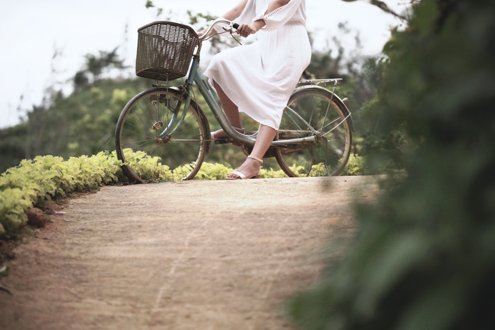 a woman riding a bike down a dirt road