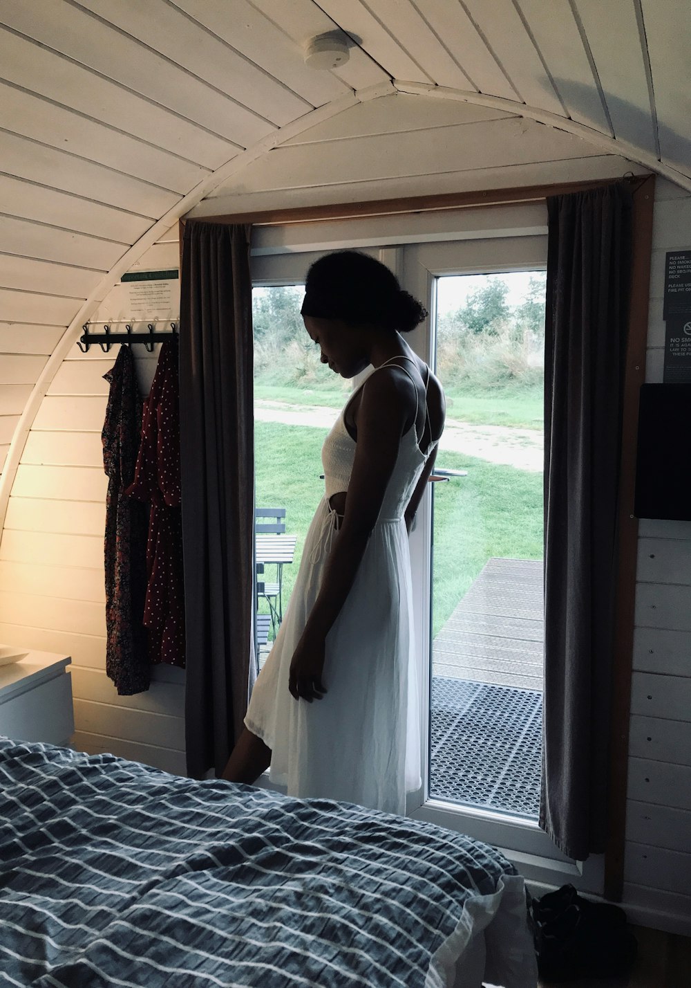 a woman in a white dress standing in front of a window