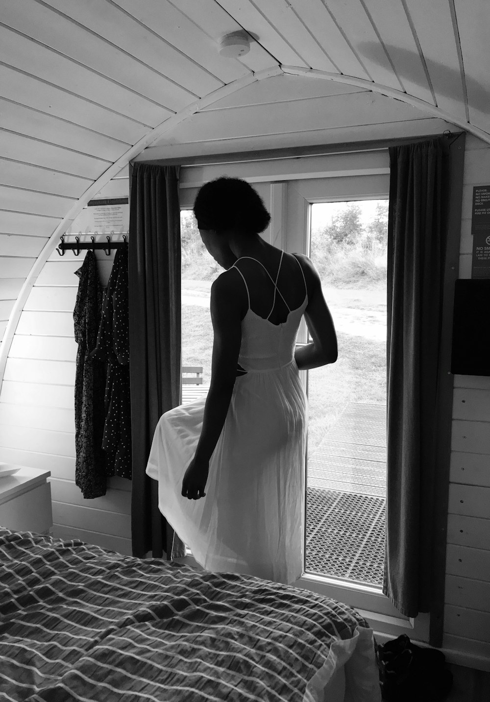 a woman in a white dress looking out a window