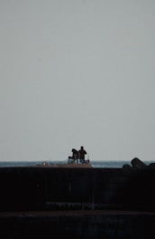a couple of people sitting on top of a pier