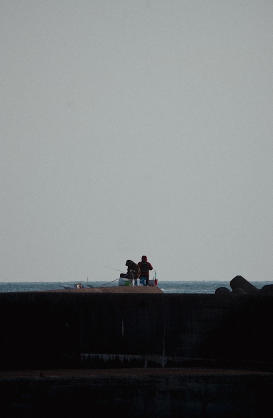 a couple of people sitting on top of a pier