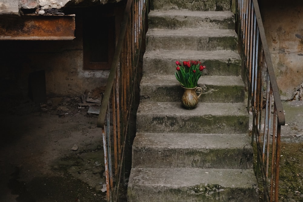 a vase with flowers sitting on a set of stairs