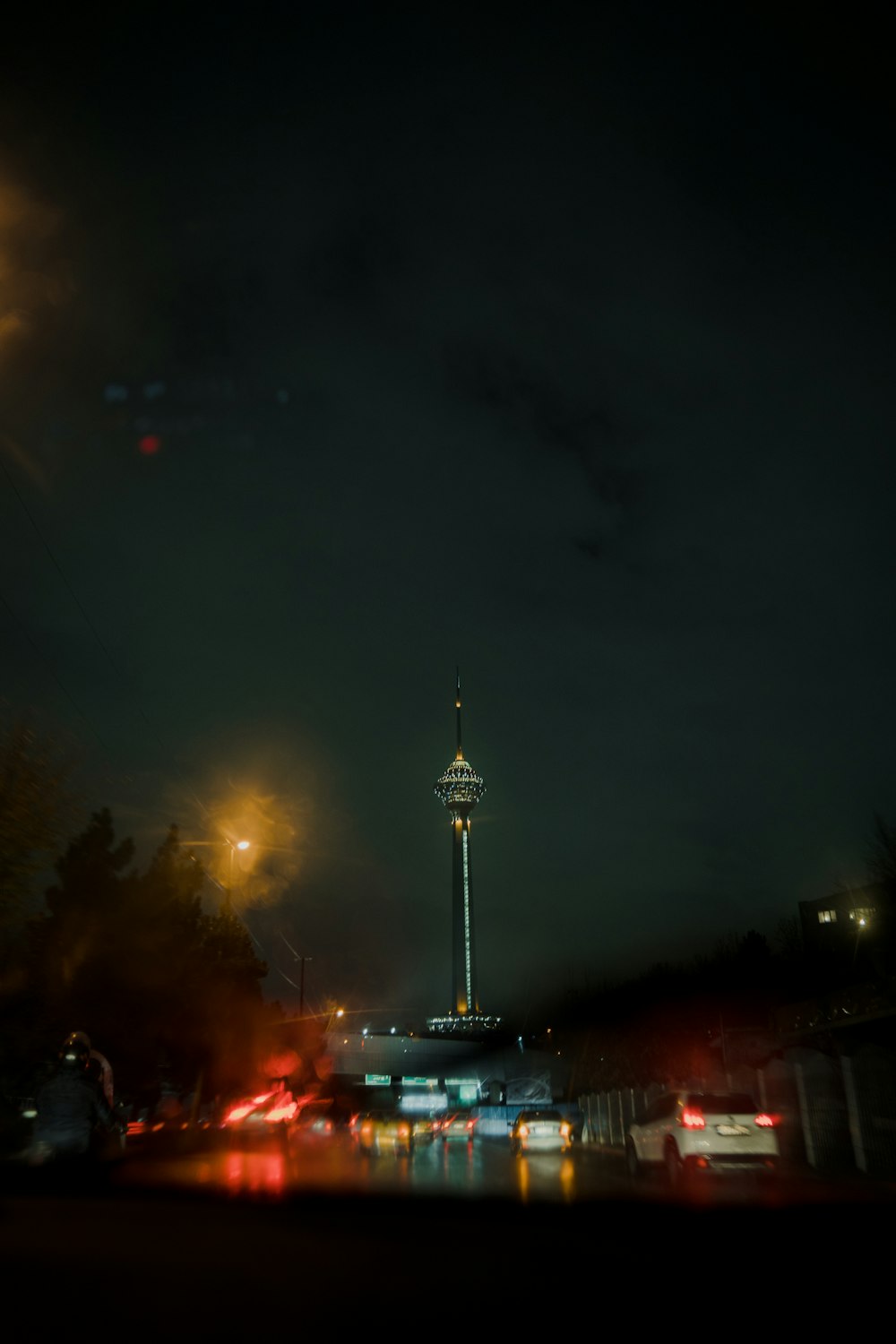a night time view of a street with a tower in the background