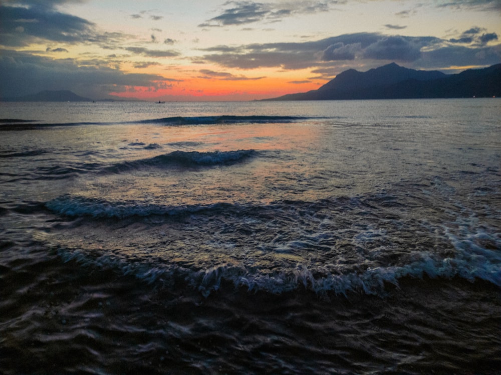 the sun is setting over the ocean with waves