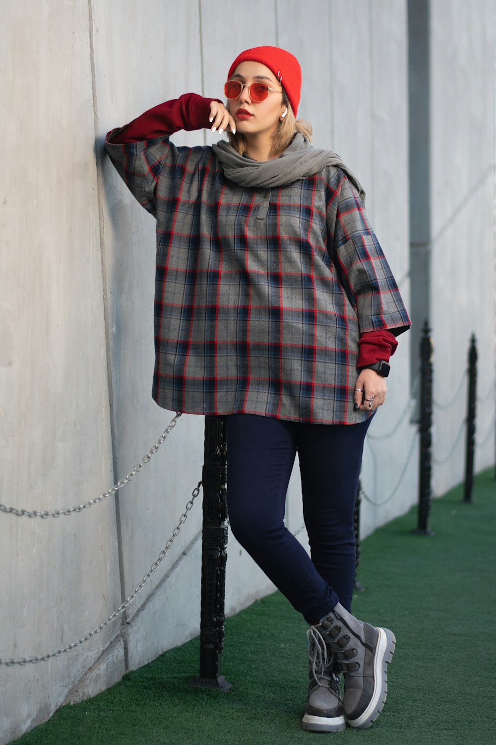 a woman leaning against a wall wearing a red hat