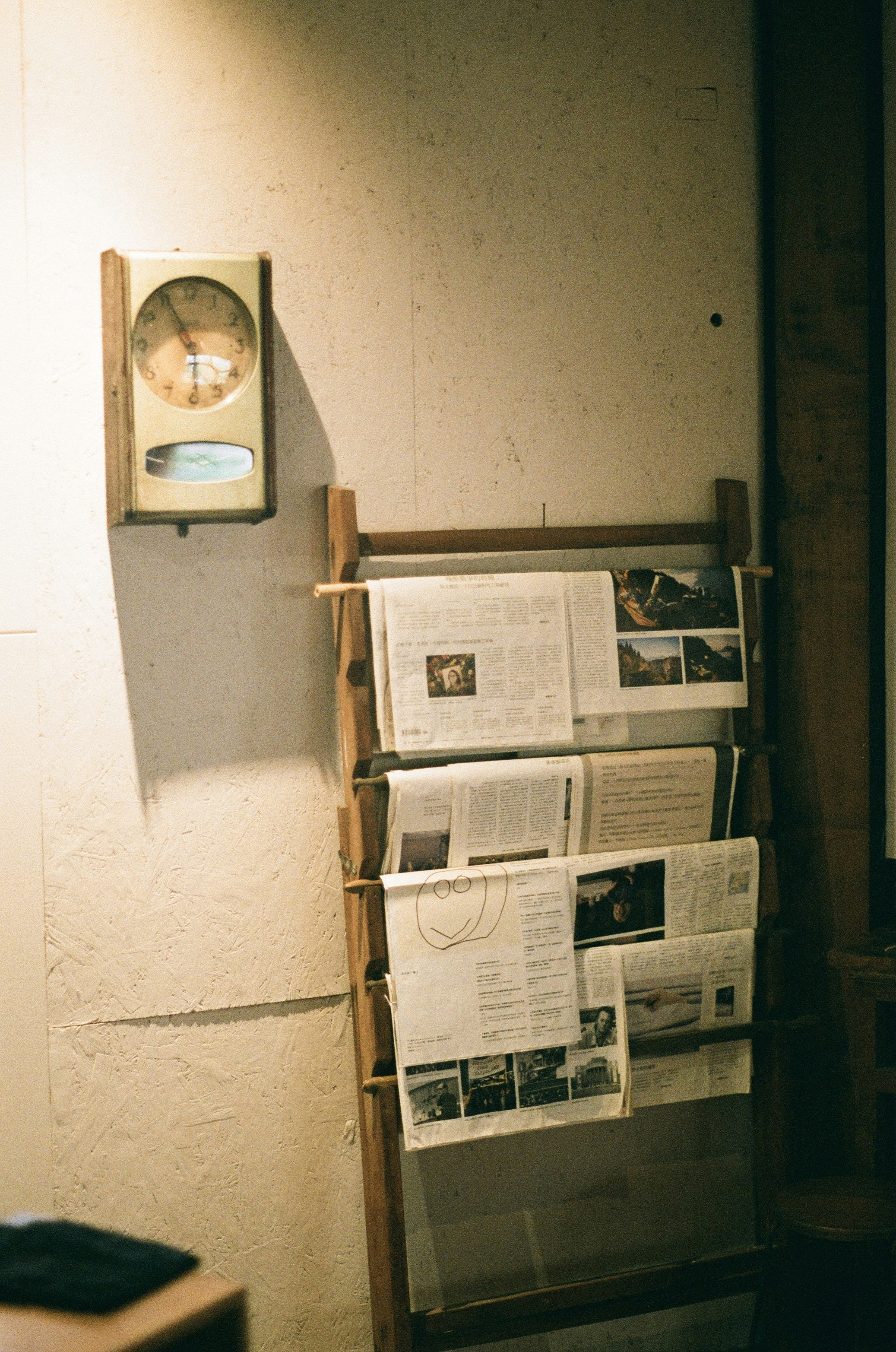 a newspaper rack with a clock on the wall
